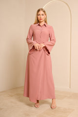 Woman wearing a pink dress standing against a beige background